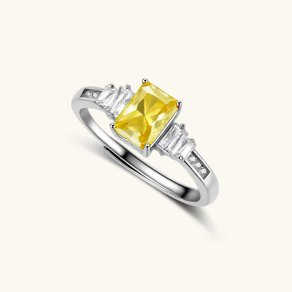 Sterling silver ring with emerald-cut yellow moissanite center stone and clear baguette side stones in elegant setting