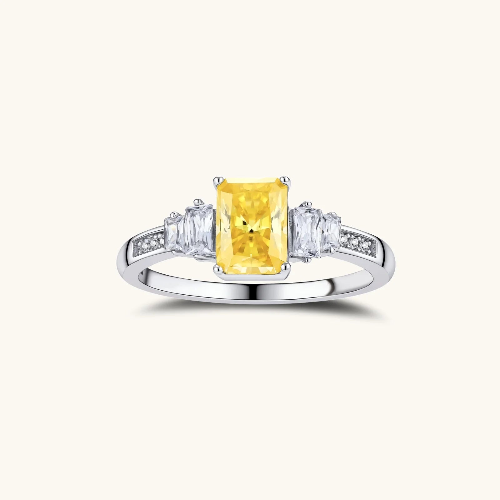 Sterling silver ring with emerald-cut yellow moissanite center stone and clear baguette side stones in elegant setting