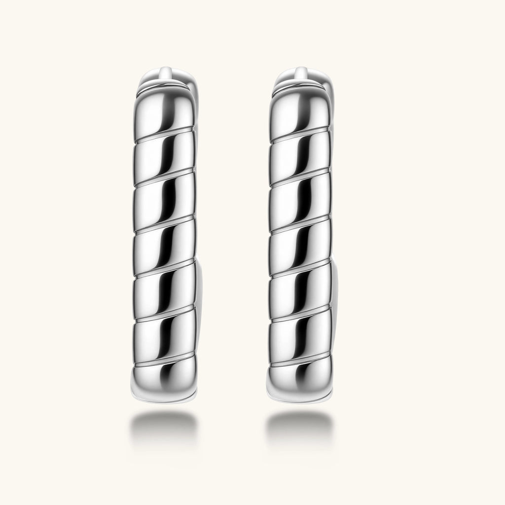 Close-up of platinum-plated sterling silver hoop earrings with horizontal textured grooves on white background.