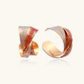 Sculptural gold-plated hoop earrings with diagonal purple and coral enamel stripes in twisted ribbon design
