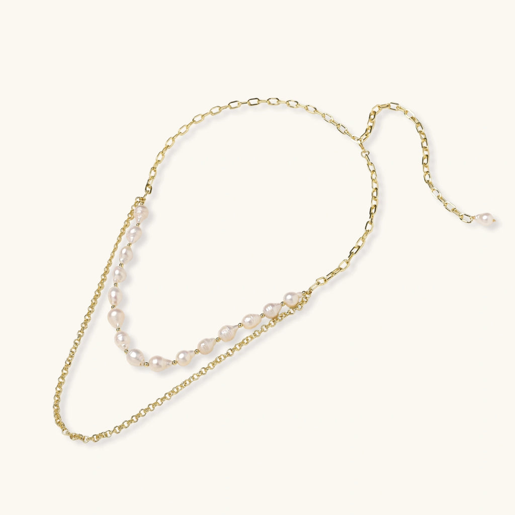 Layered gold chain necklace with organic baroque freshwater pearls and adjustable length on cream background