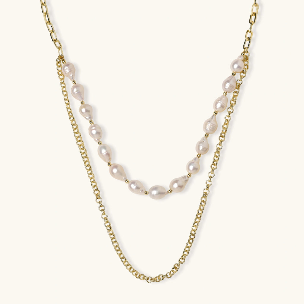 Layered gold chain necklace with organic baroque freshwater pearls and adjustable length on cream background