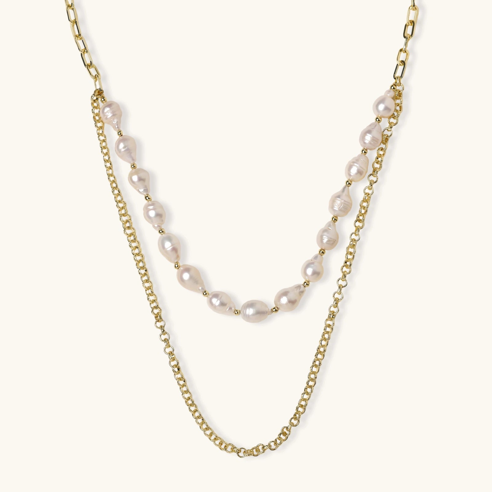 Layered gold chain necklace with organic baroque freshwater pearls and adjustable length on cream background
