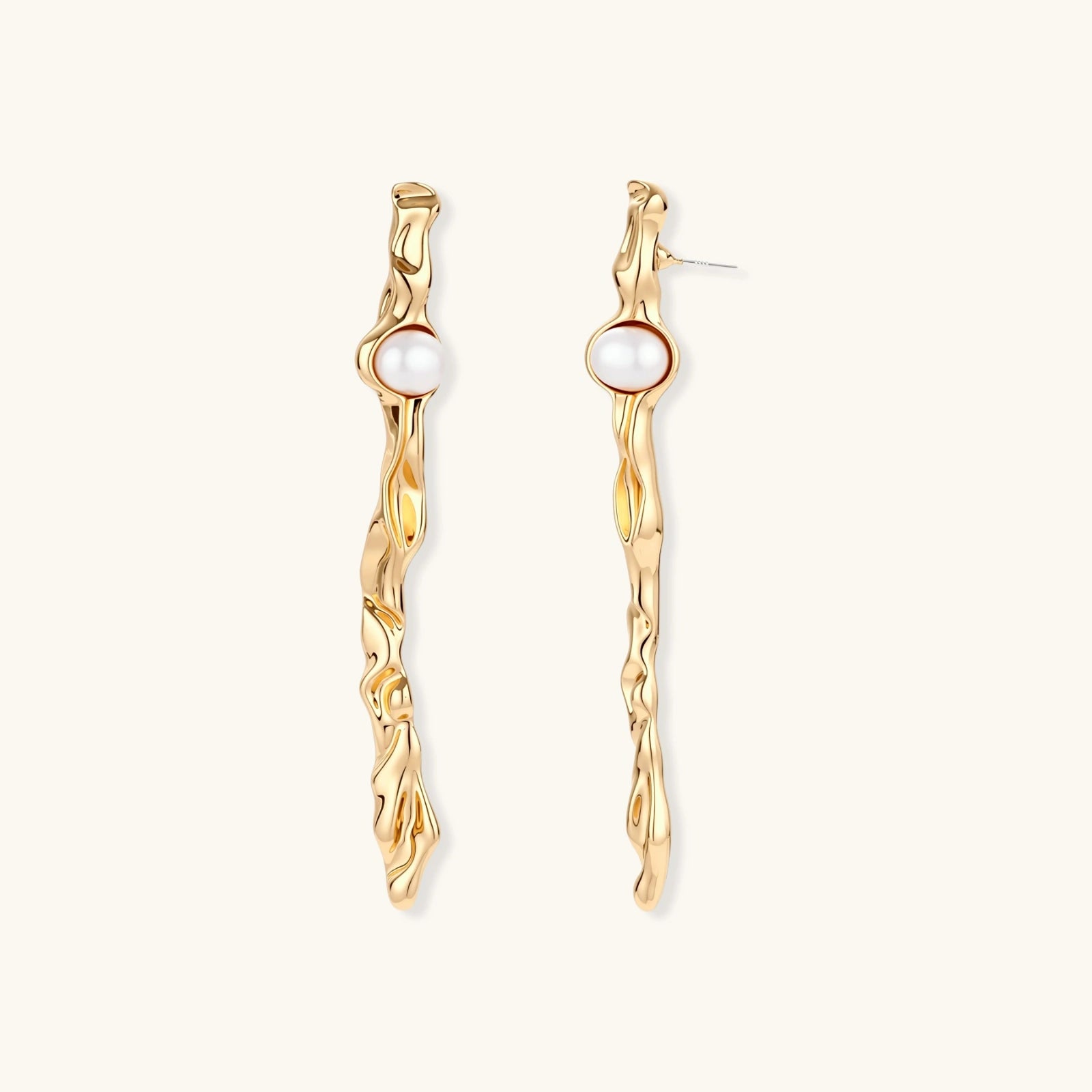 Organic twisted gold-toned drop earrings with white ABS pearls positioned near the top on cream background.