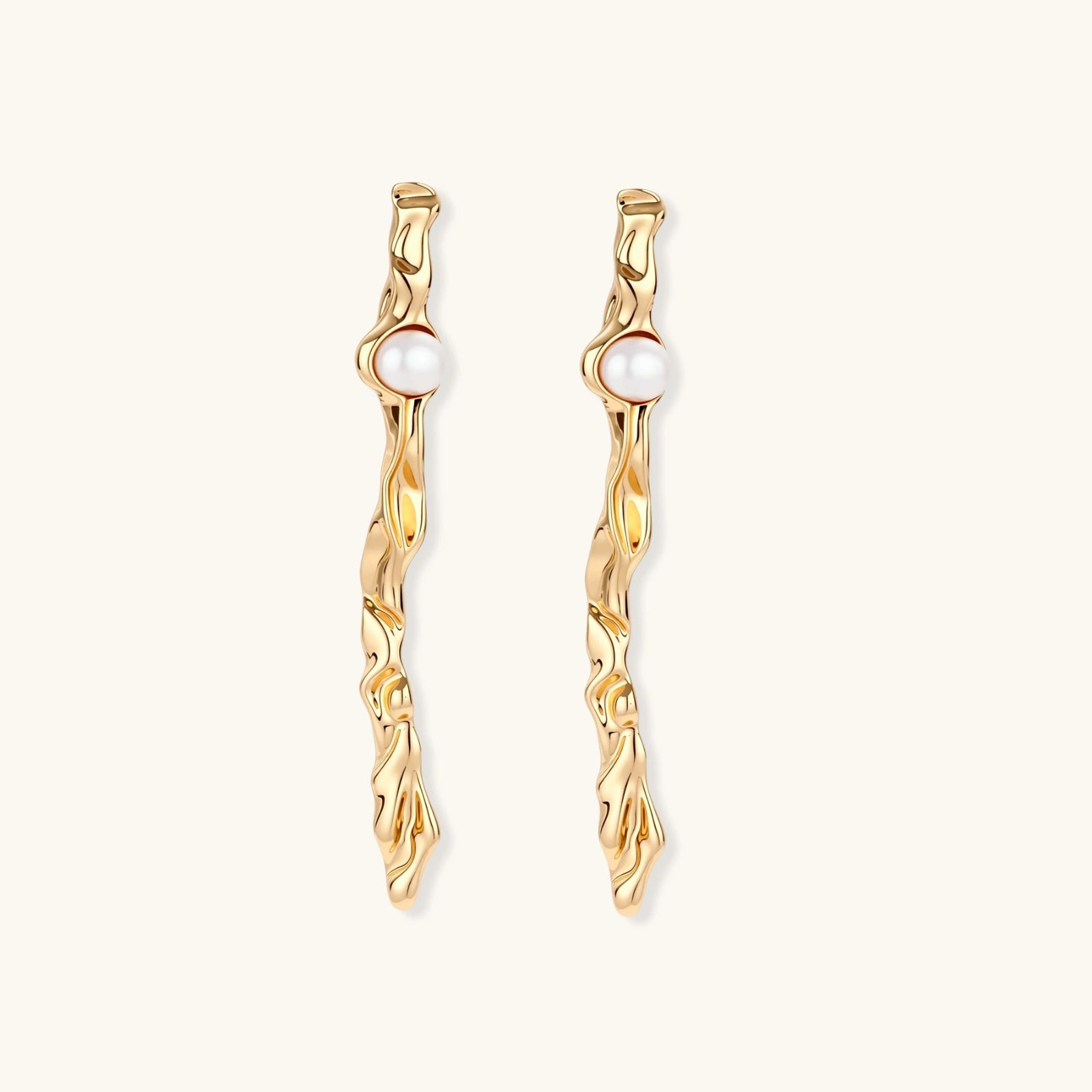 Organic twisted gold-toned drop earrings with white ABS pearls positioned near the top on cream background.