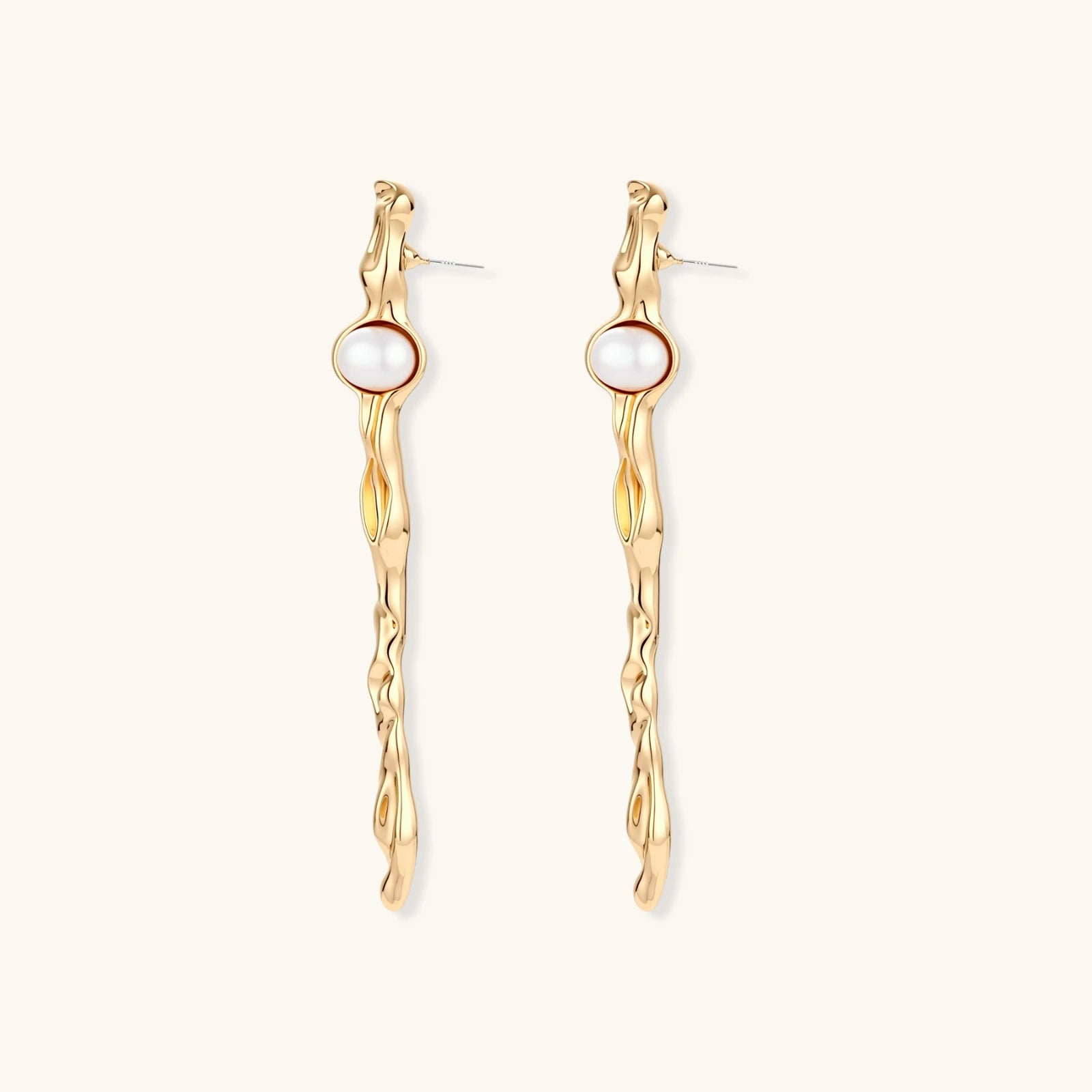 Organic twisted gold-toned drop earrings with white ABS pearls positioned near the top on cream background.