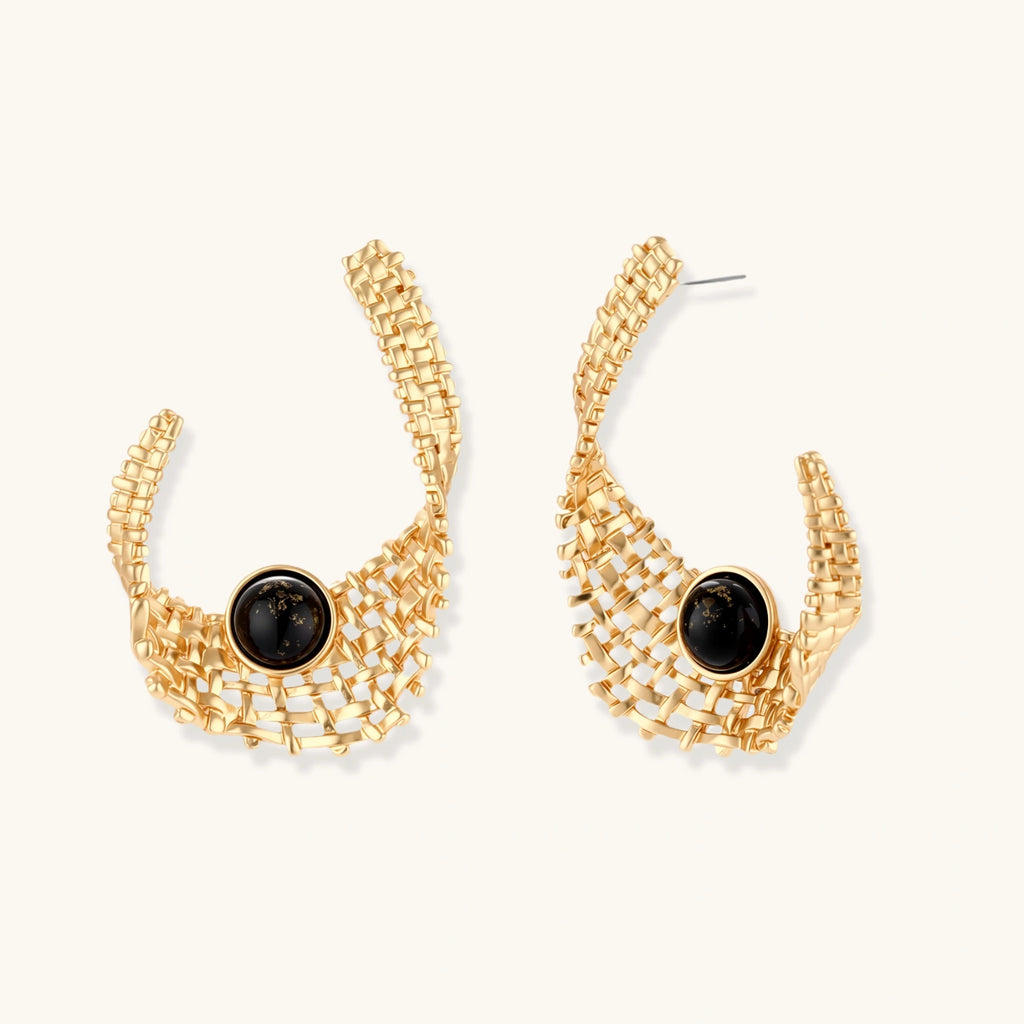 Gold-tone sculptural earrings with interwoven mesh design and black resin stone accents on white background.