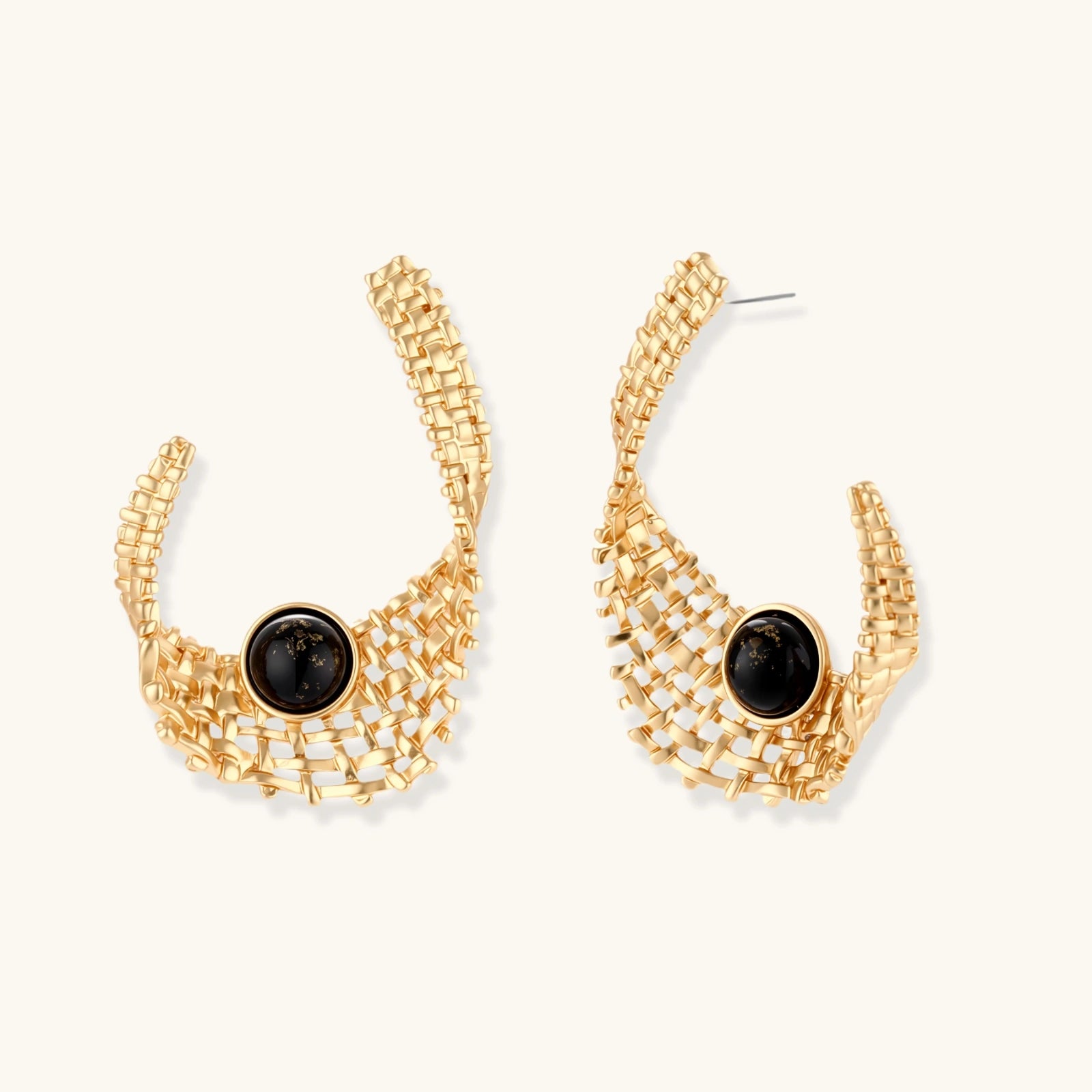 Gold-tone sculptural earrings with interwoven mesh design and black resin stone accents on white background.