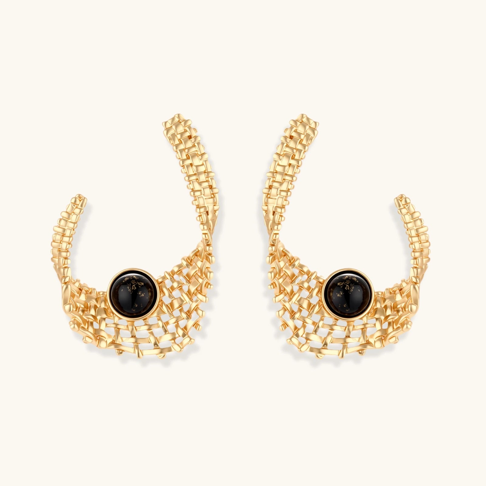 Gold-tone sculptural earrings with interwoven mesh design and black resin stone accents on white background.