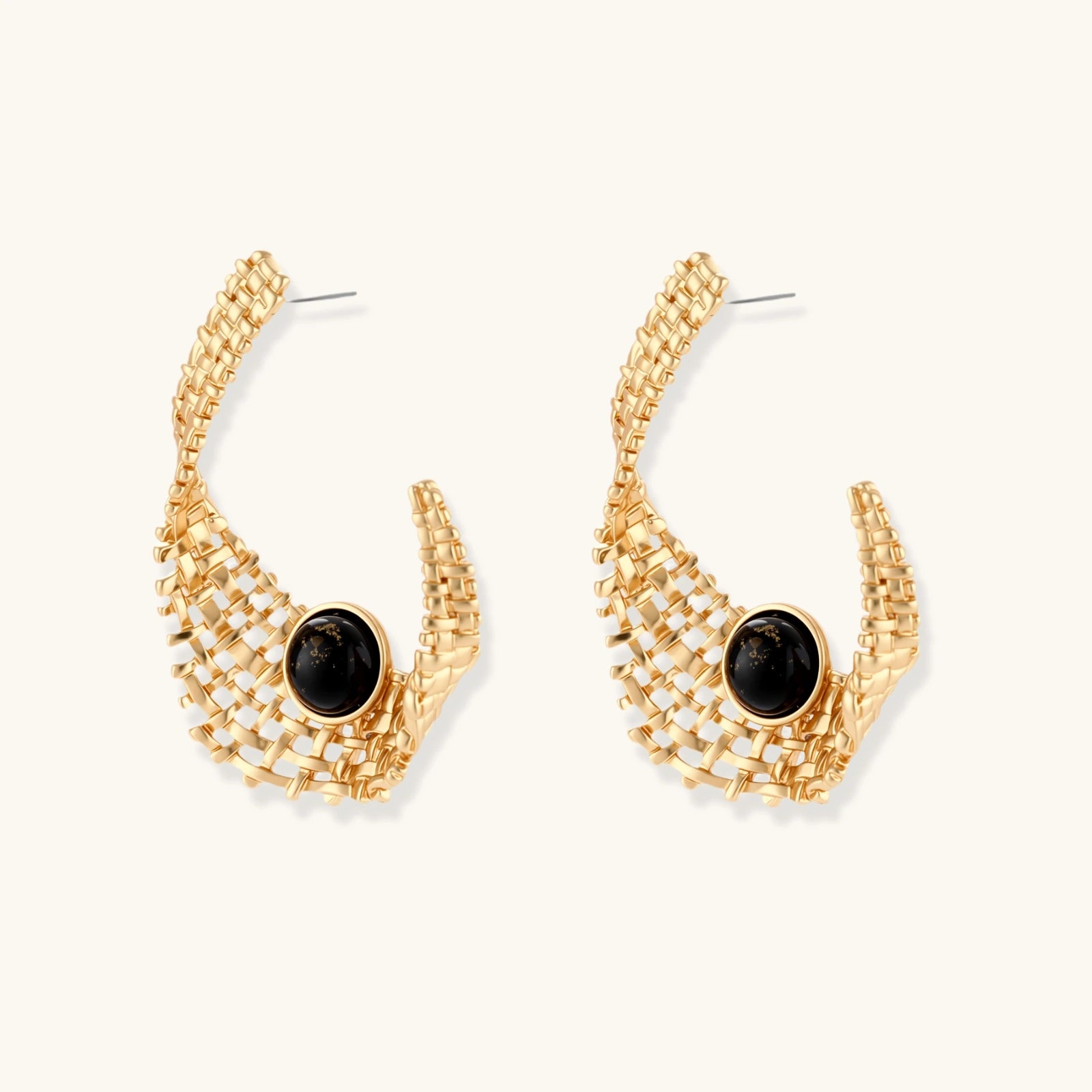 Gold-tone sculptural earrings with interwoven mesh design and black resin stone accents on white background.