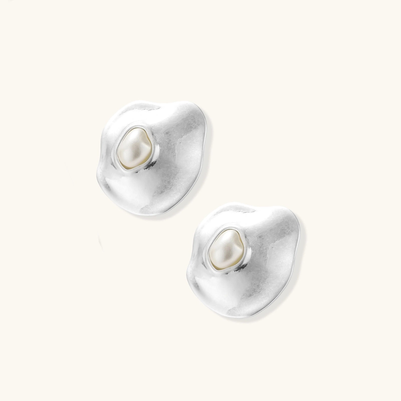 Organic silver stud earrings with white resin pearl centers in fluid stone-like shapes on light background.