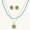 Gold-plated turquoise jewelry set with circular medallion pendant, beaded necklace, and matching stud earrings on white background