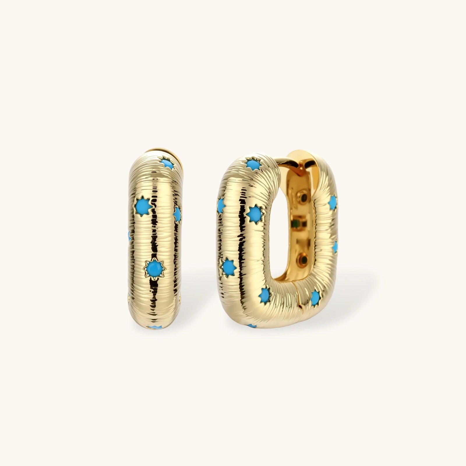 Gold-plated huggie hoop earrings with blue star inlays and textured surface, shown against white background.