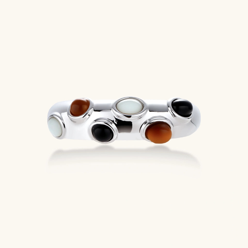 Adjustable platinum-plated ring with multiple oval cabochon stones in black, amber, and white tones on neutral background.