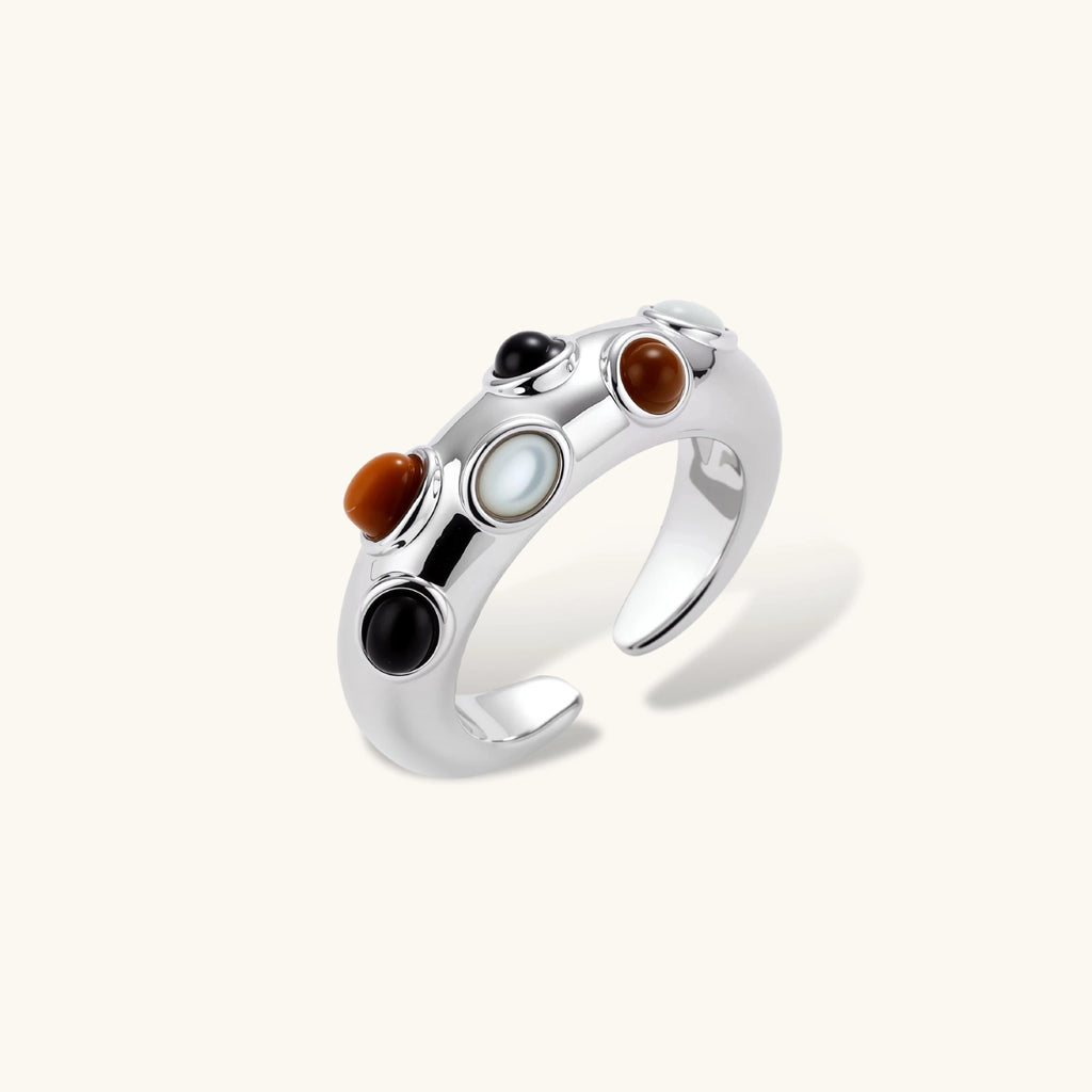 Adjustable platinum-plated ring with multiple oval cabochon stones in black, amber, and white tones on neutral background.