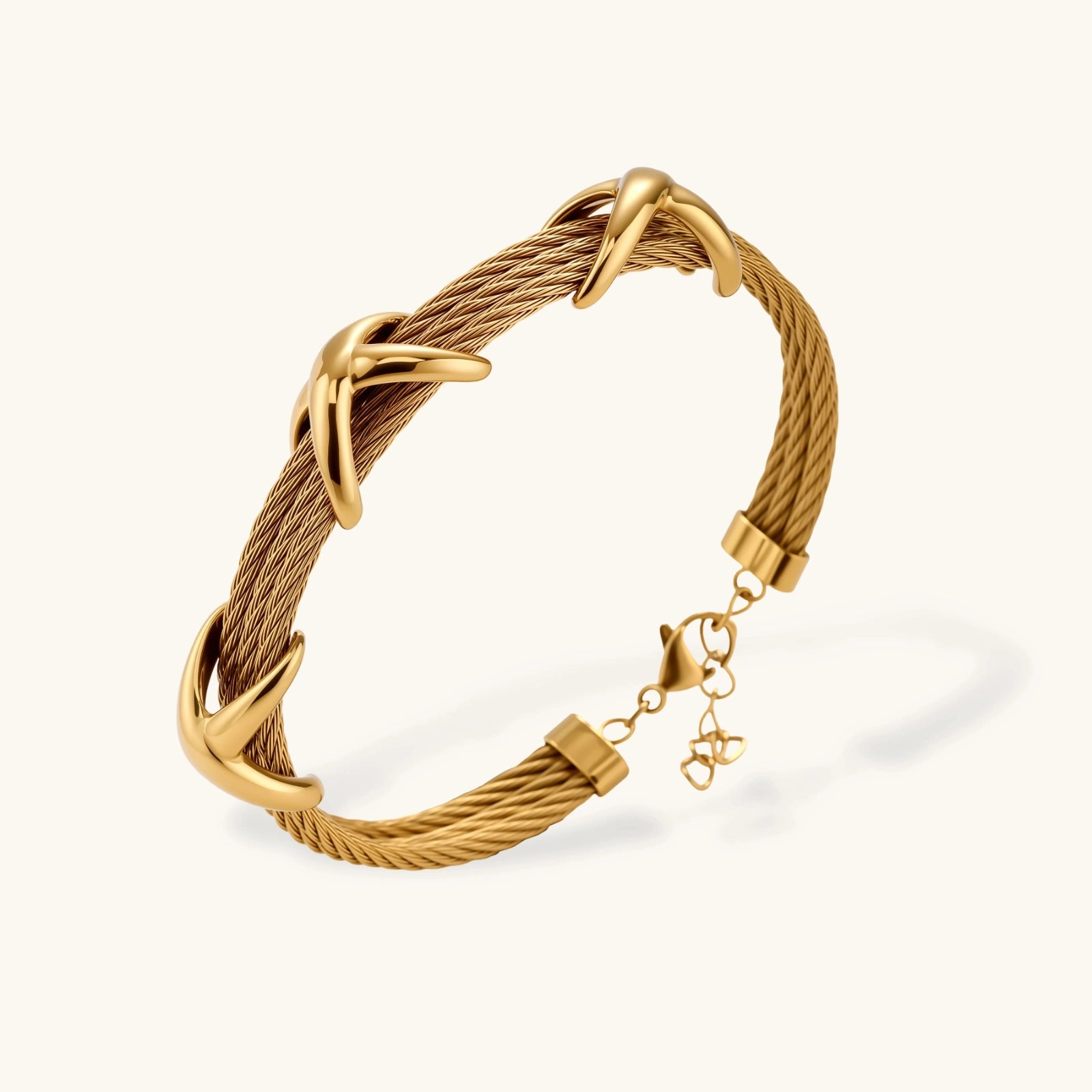 Gold-tone multi-strand twisted cable bracelet with polished X-cross knot accents and adjustable lobster clasp chain.