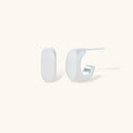 Pair of small silver-plated huggie hoop earrings with clean minimal design on neutral background.
