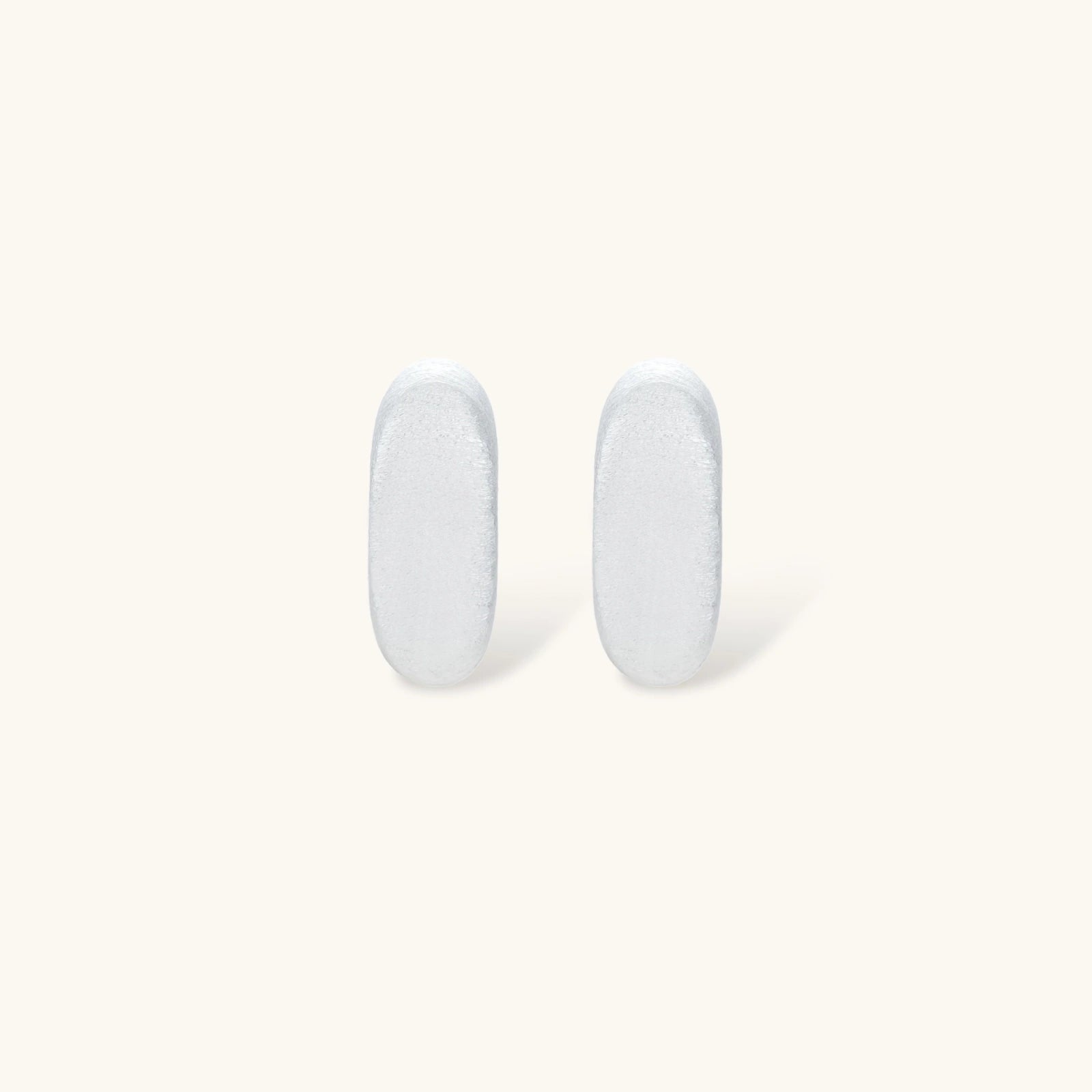 Pair of small silver-plated huggie hoop earrings with clean minimal design on neutral background.