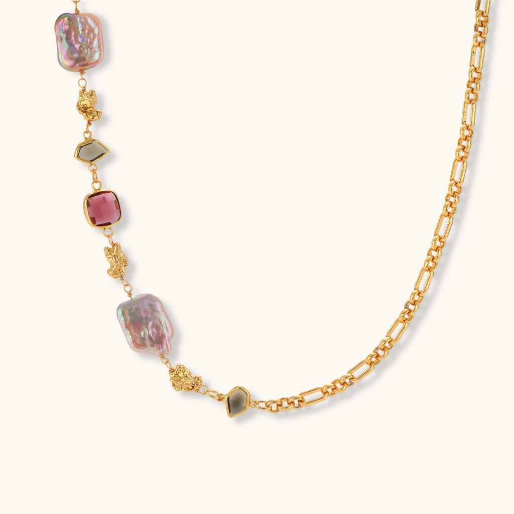 18k gold-plated chain necklace with iridescent baroque pearls and burgundy gemstones on white background.