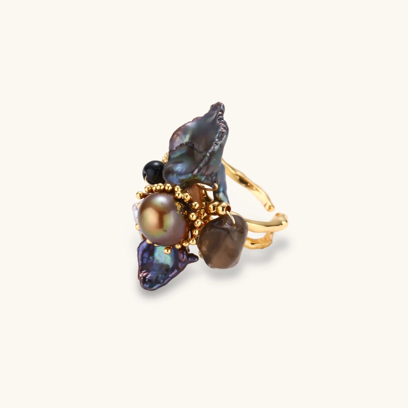 Adjustable gold-plated ring featuring clustered dark baroque pearls in organic arrangement on white background.