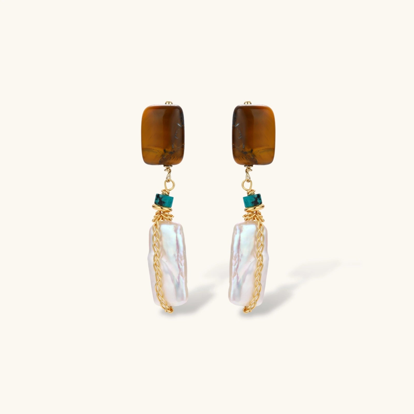 Gold-plated drop earrings with amber stones, teal beads, and wire-wrapped baroque pearls on cream background.
