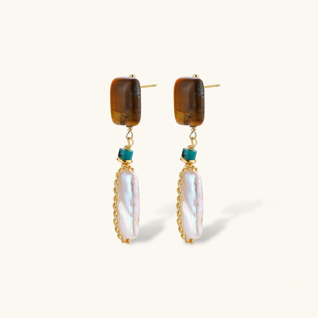 Gold-plated drop earrings with amber stones, teal beads, and wire-wrapped baroque pearls on cream background.