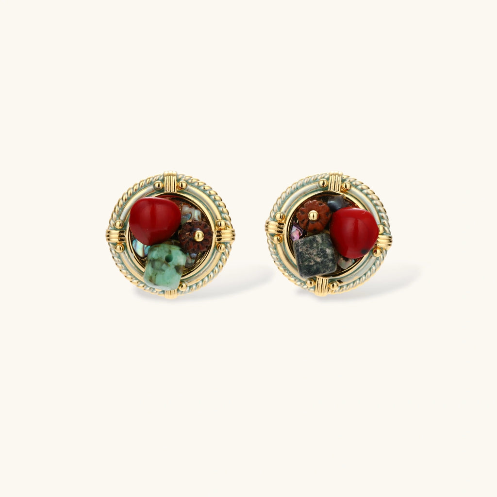 Circular gold-plated earrings with turquoise, coral, wood beads, and rope border detail on cream background.