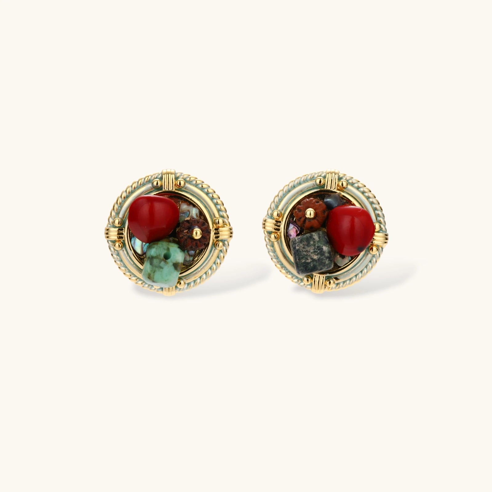 Circular gold-plated earrings with turquoise, coral, wood beads, and rope border detail on cream background.