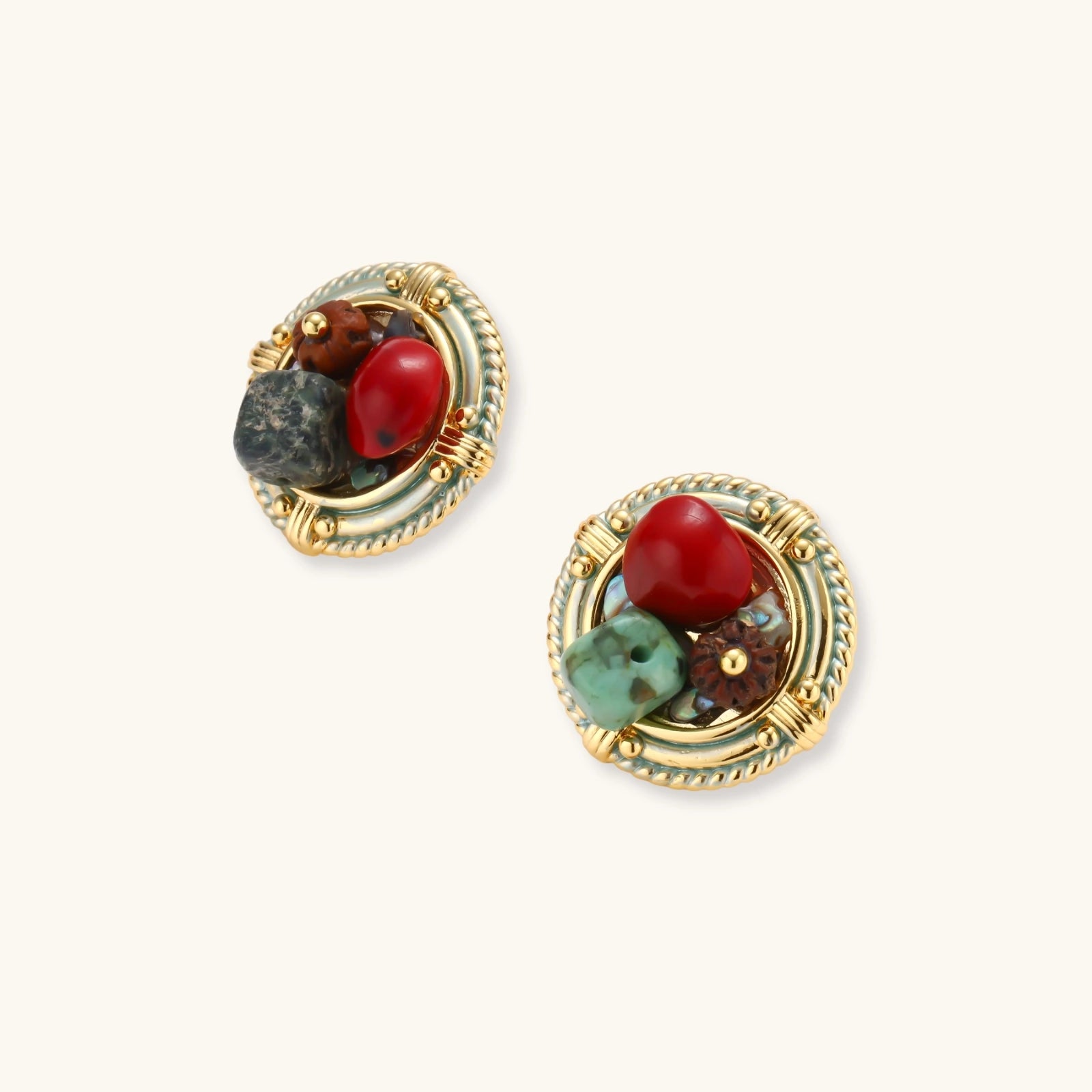Circular gold-plated earrings with turquoise, coral, wood beads, and rope border detail on cream background.