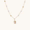 Delicate 18k gold-plated chain with baroque pearls and colorful enamel pendant featuring blue, pink accents on cream background.