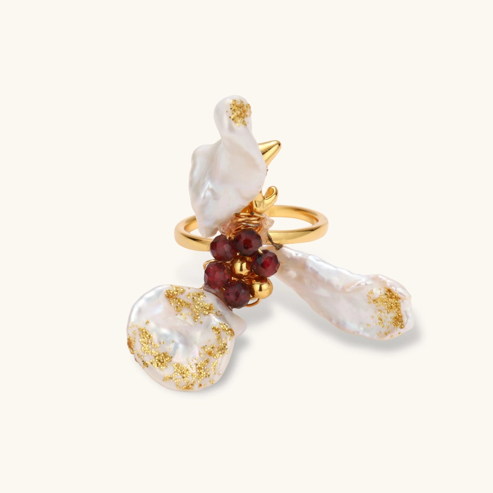 Adjustable gold-plated ring featuring clustered baroque pearls with golden inclusions and burgundy gemstones in sculptural arrangement.