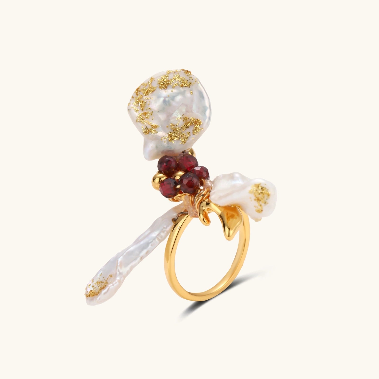 Adjustable gold-plated ring featuring clustered baroque pearls with golden inclusions and burgundy gemstones in sculptural arrangement.