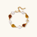 Elegant bracelet with alternating baroque pearls and amber teardrop gemstones set in 18k gold-plated copper on cream background.