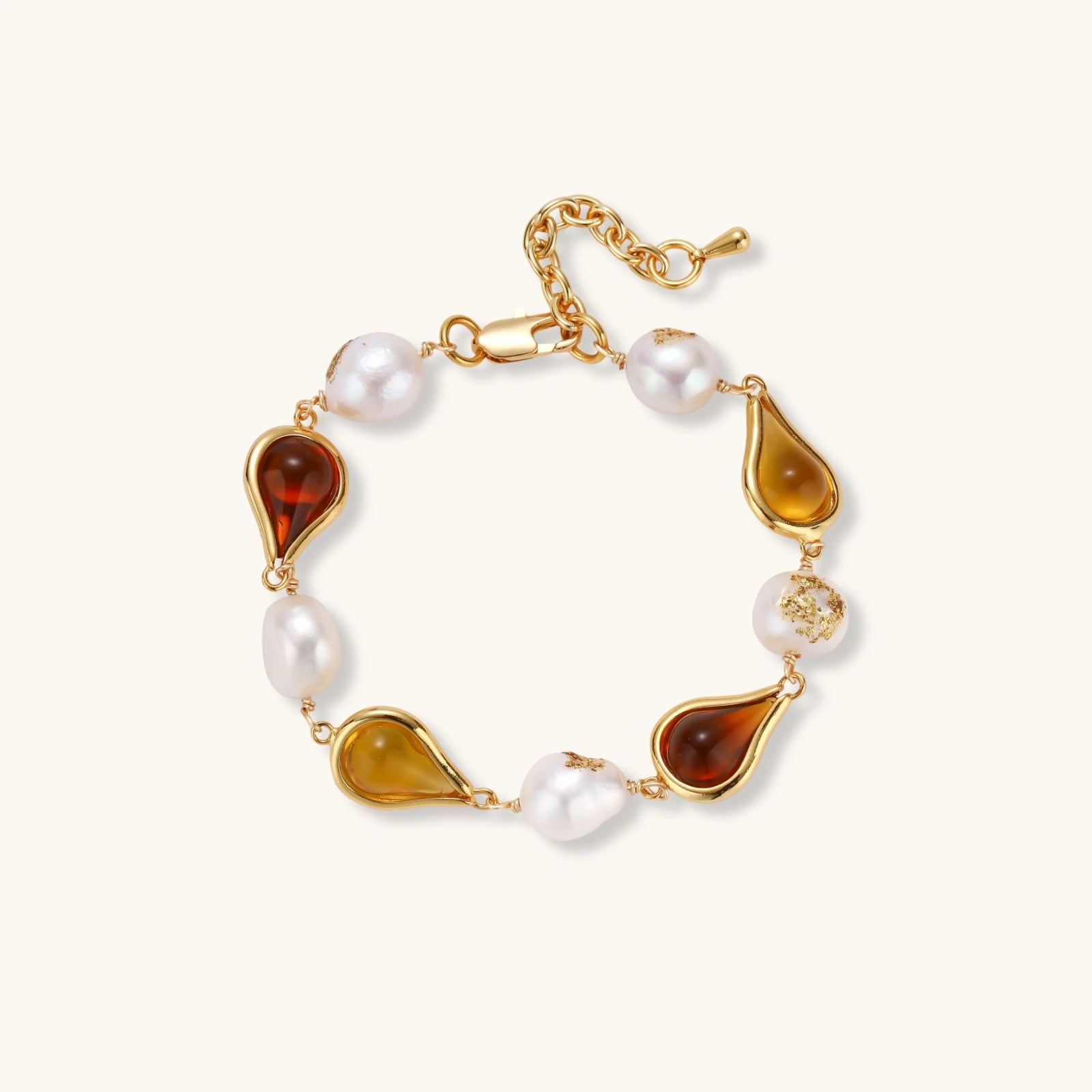 Elegant bracelet with alternating baroque pearls and amber teardrop gemstones set in 18k gold-plated copper on cream background.