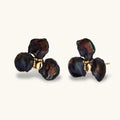 Dark iridescent baroque pearls arranged in flower pattern with 18K gold-plated center on cream background.