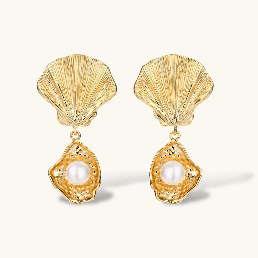 Gold shell-shaped drop earrings with scallop tops and oyster bottoms featuring round freshwater pearls on white background.