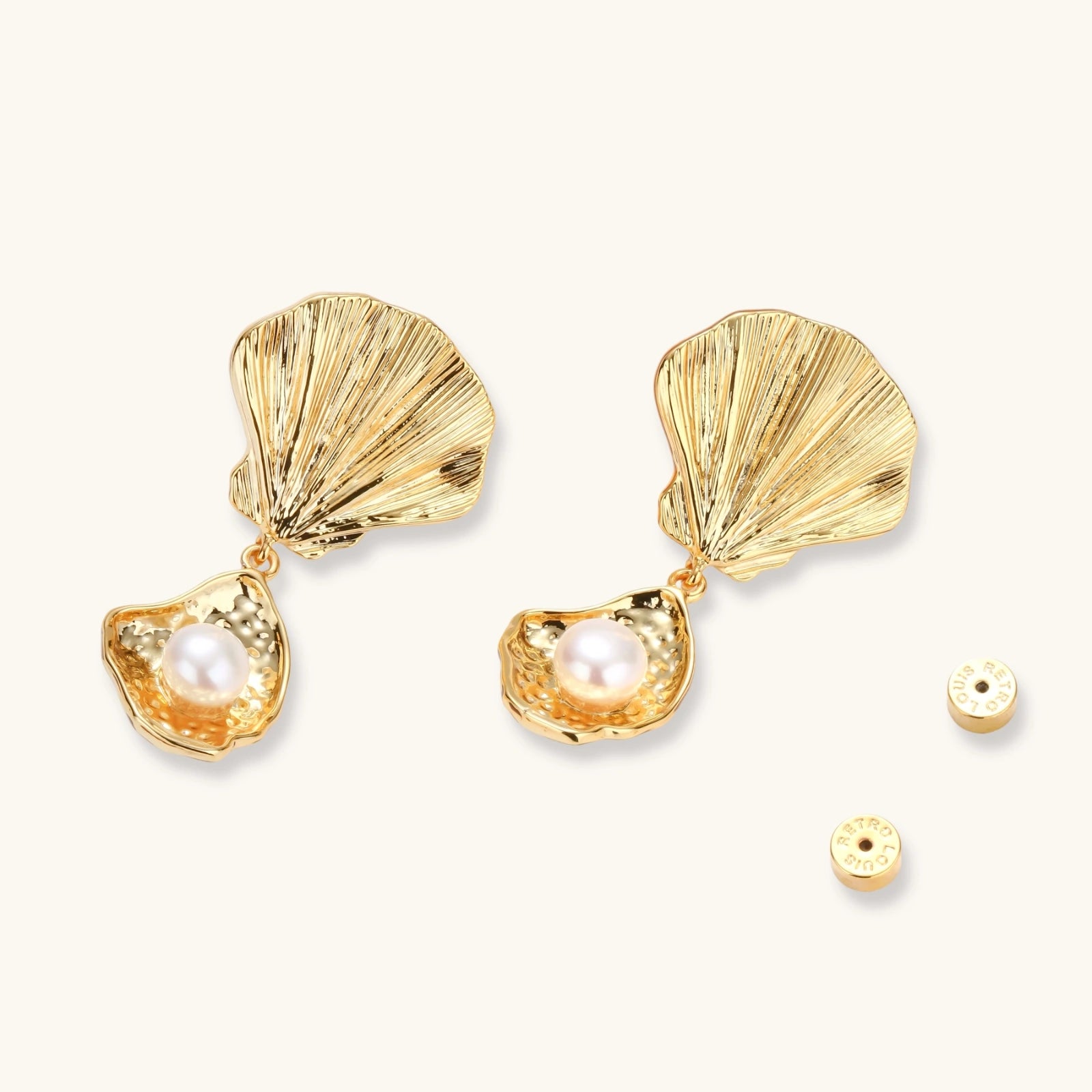 Gold shell-shaped drop earrings with scallop tops and oyster bottoms featuring round freshwater pearls on white background.