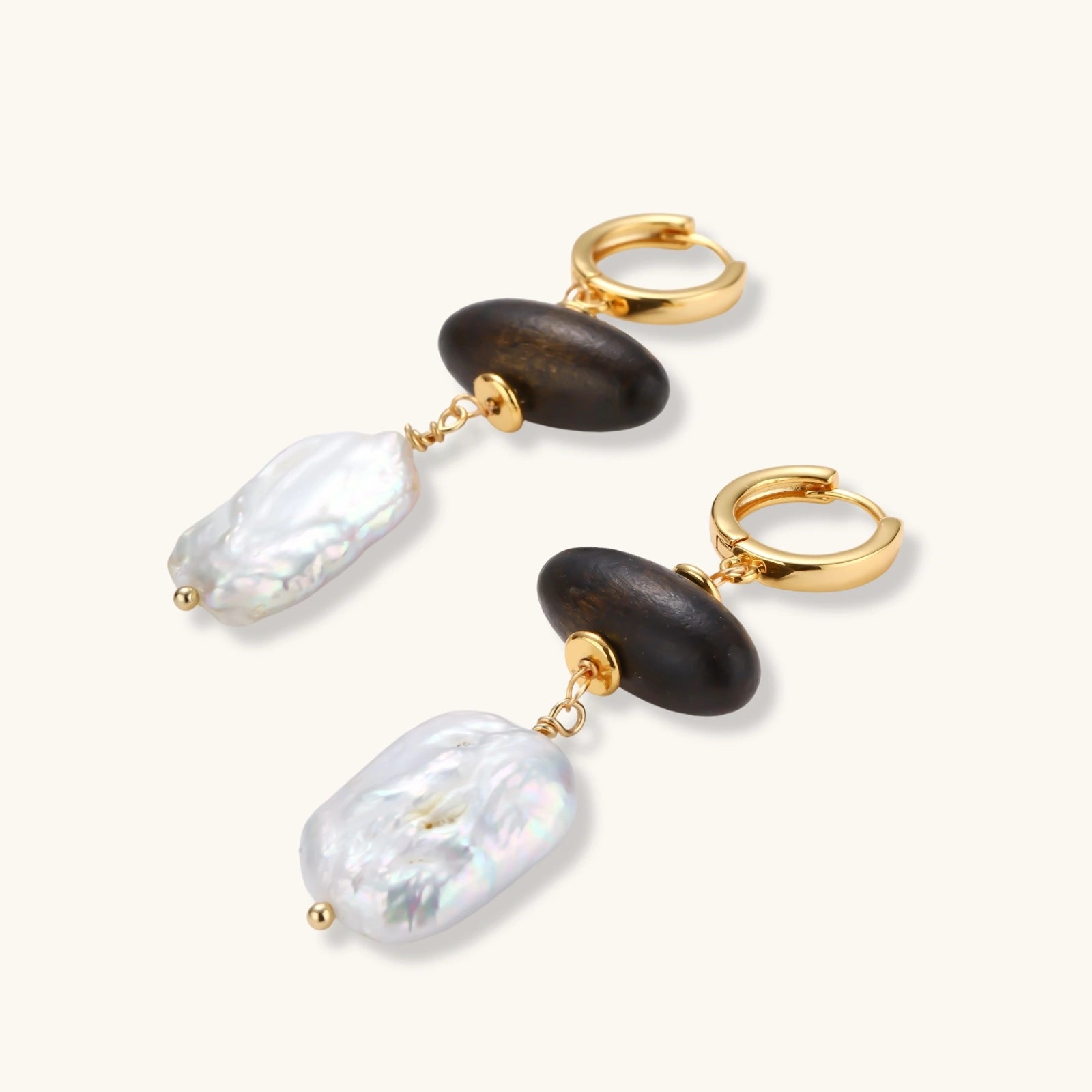 Gold hoop earrings with dark wood beads and baroque freshwater pearls, shown from multiple angles on cream background.
